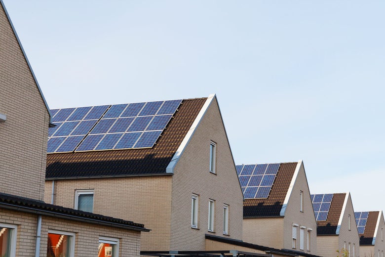 A row of identical houses with solar panels on their roofs.